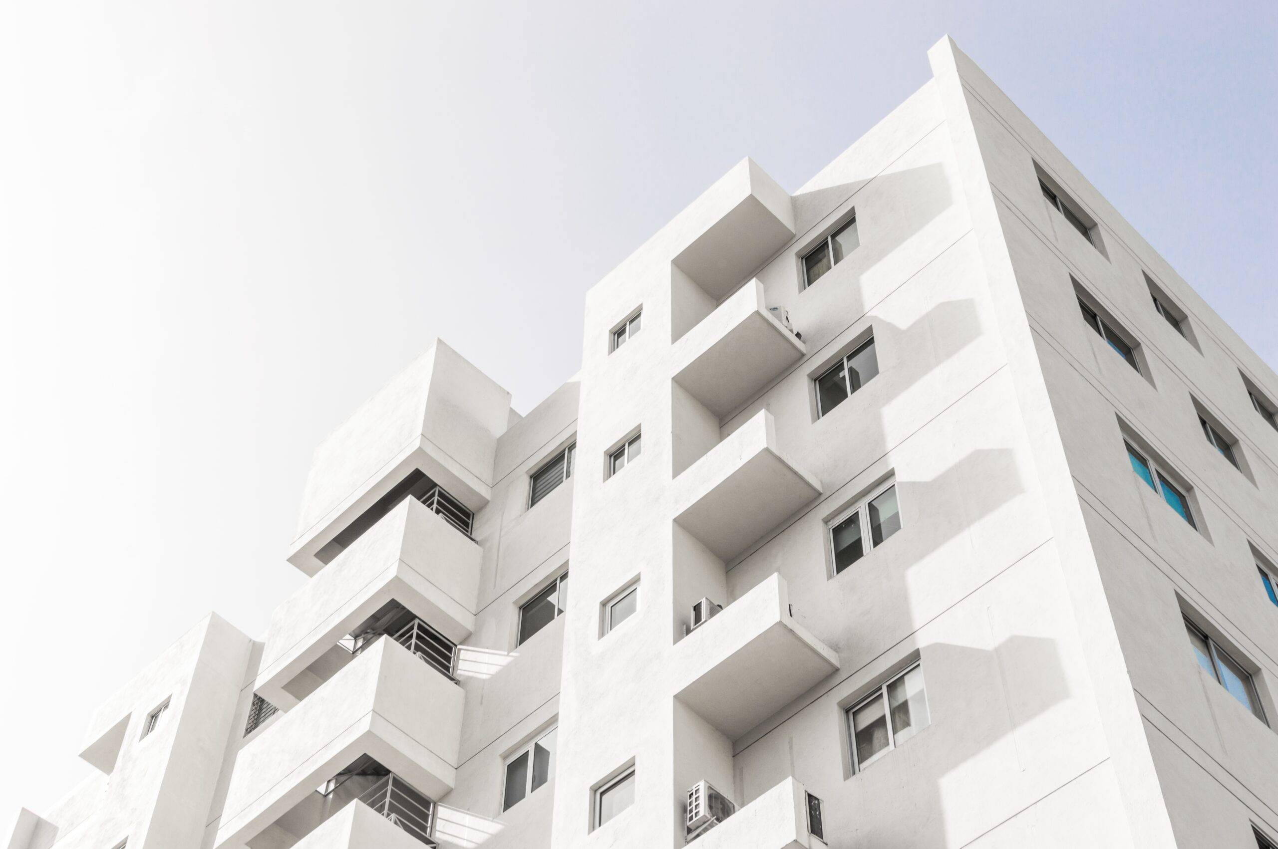 Low angle shot of a facade of a white modern building under a blue clear sky A low angle shot of a facade of a white modern building under a blue clear sky
